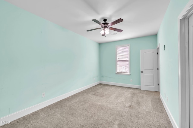 spare room with baseboards, carpet floors, visible vents, and a ceiling fan