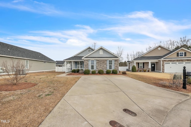 craftsman-style house featuring stone siding, concrete driveway, and fence