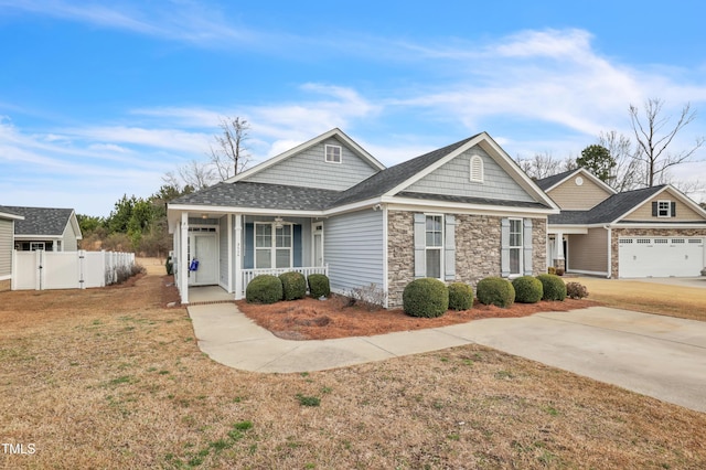 view of front of home with a front lawn, fence, covered porch, stone siding, and a gate