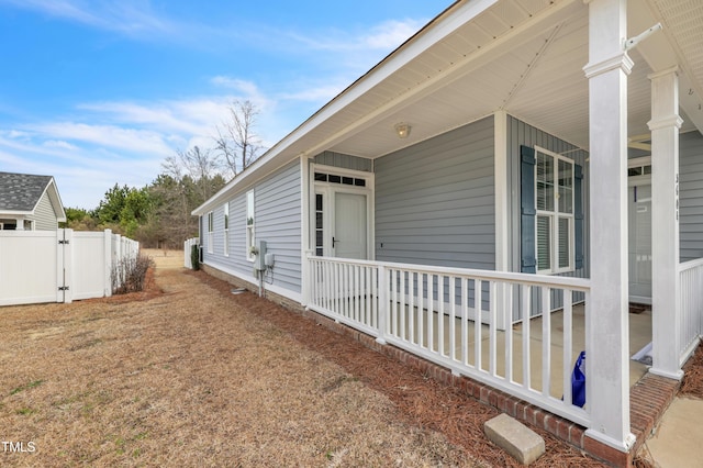 view of side of home featuring fence, a porch, and a gate