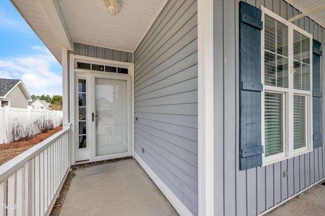 doorway to property with board and batten siding and fence