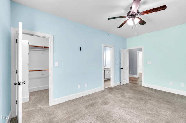 unfurnished bedroom featuring a walk in closet, baseboards, a closet, and carpet floors