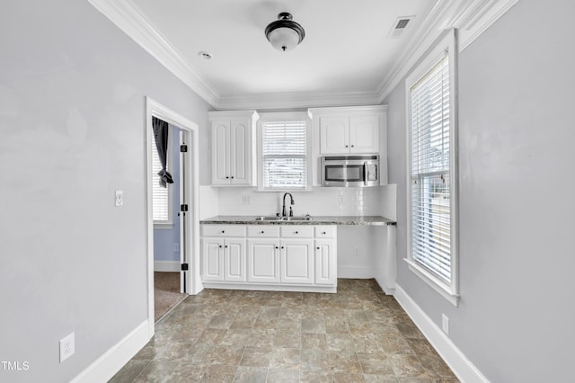 kitchen with stainless steel microwave, visible vents, crown molding, white cabinetry, and a sink