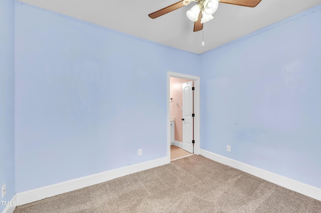 empty room featuring a ceiling fan, light colored carpet, and baseboards