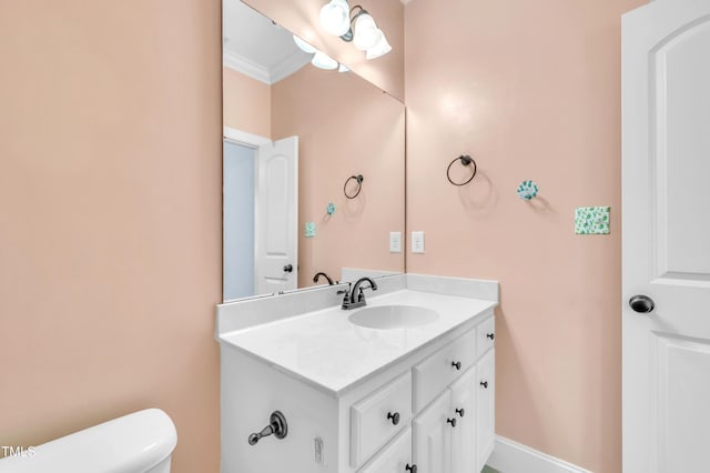 bathroom featuring vanity, toilet, baseboards, and ornamental molding