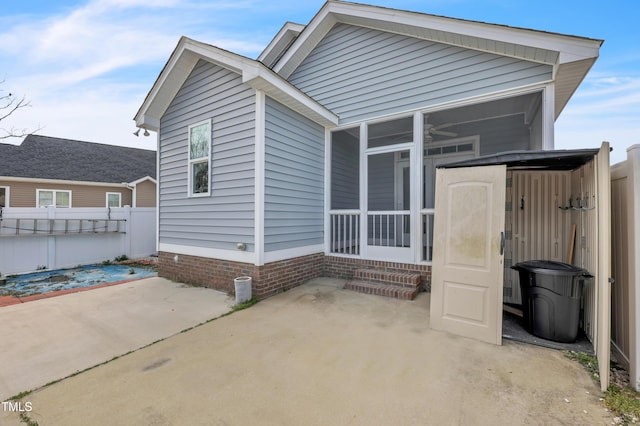 rear view of house featuring a patio area, fence, and a sunroom