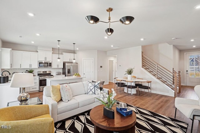 living area featuring light wood-type flooring, baseboards, stairway, and recessed lighting