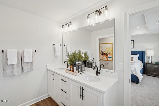 bathroom with baseboards, a sink, ensuite bathroom, and double vanity