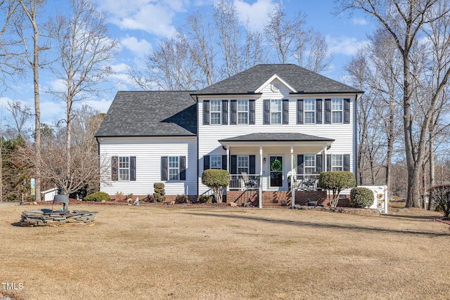 colonial home with a porch, roof with shingles, and a front lawn