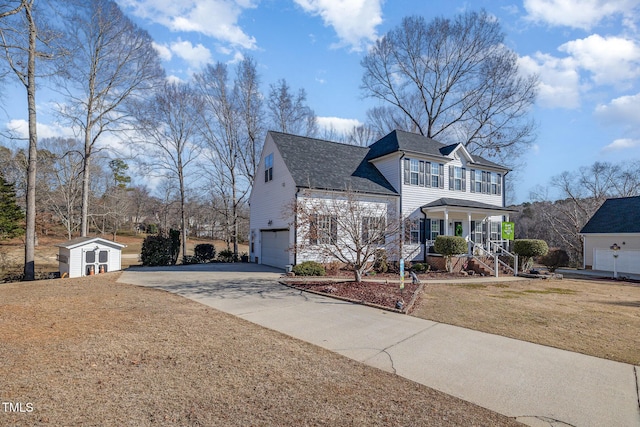 traditional home featuring an attached garage, covered porch, an outdoor structure, concrete driveway, and a storage unit