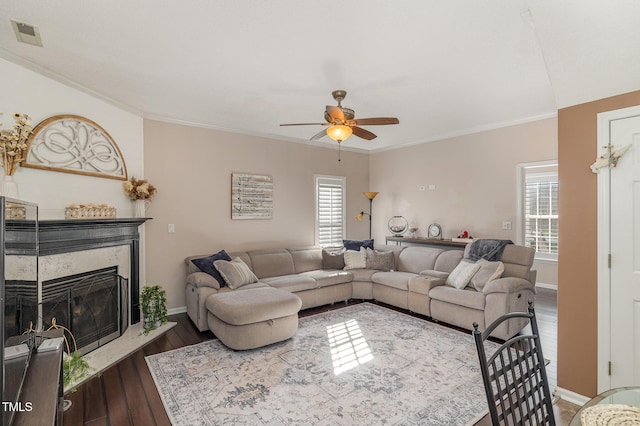 living area with crown molding, a fireplace, visible vents, and wood finished floors