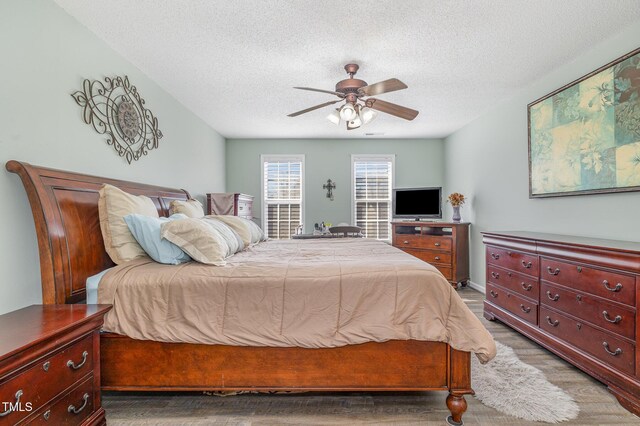 bedroom with a textured ceiling, ceiling fan, wood finished floors, and baseboards