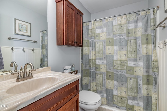 full bath with toilet, a wainscoted wall, and vanity