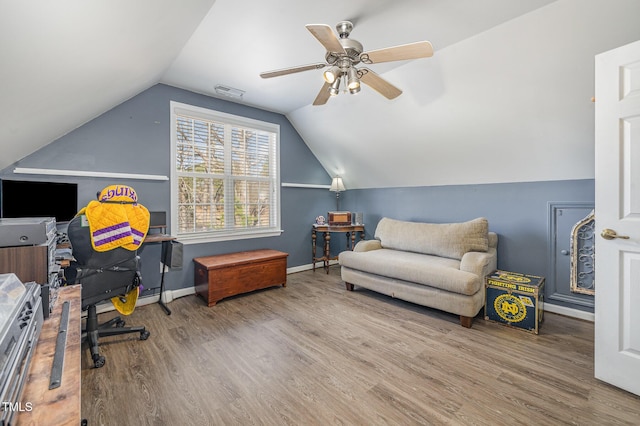 living area featuring baseboards, visible vents, a ceiling fan, wood finished floors, and vaulted ceiling