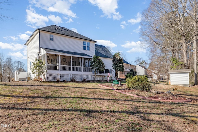 back of house with a storage shed, a yard, an outdoor structure, and a sunroom