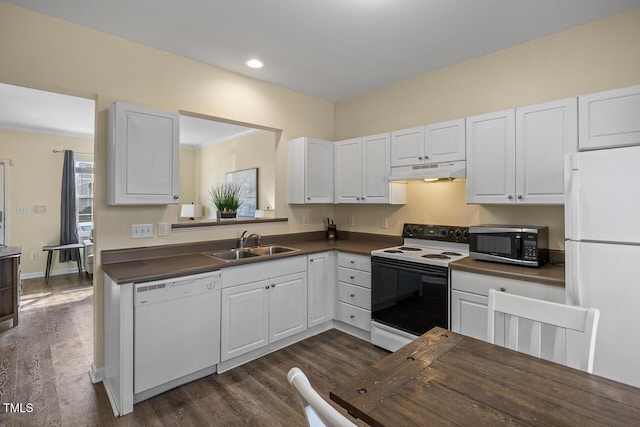 kitchen featuring white appliances, dark countertops, a sink, and under cabinet range hood