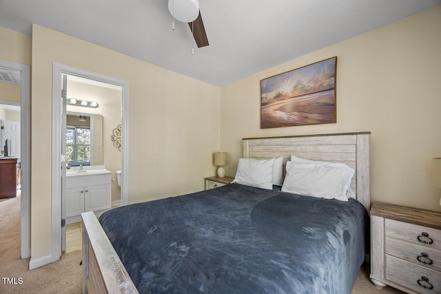 bedroom featuring a ceiling fan, light carpet, and connected bathroom