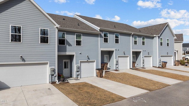 townhome / multi-family property featuring driveway and a shingled roof