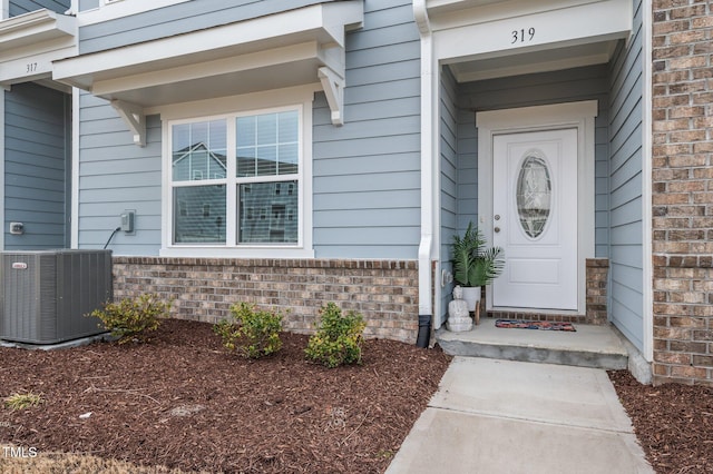 doorway to property with central AC and brick siding