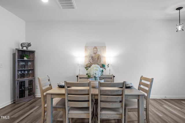 dining area with wood finished floors, visible vents, and baseboards