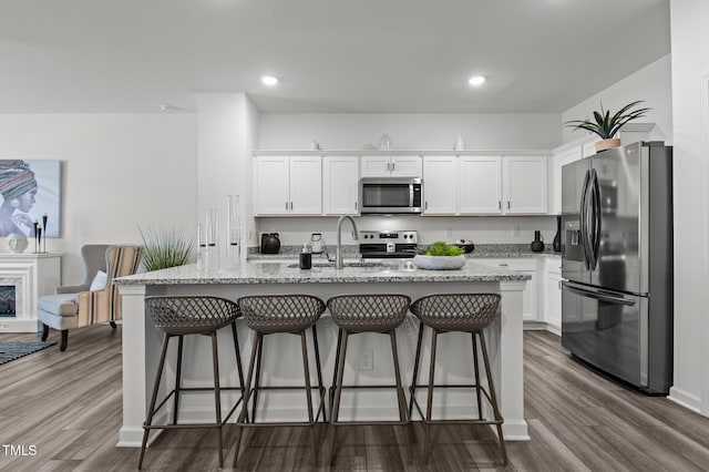 kitchen with stainless steel appliances, white cabinets, a sink, and dark wood-style floors