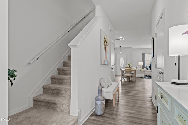 stairs featuring wood finished floors, visible vents, and baseboards