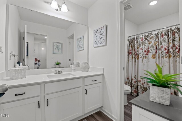 full bath with visible vents, vanity, toilet, and wood finished floors