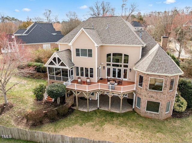 rear view of property with roof with shingles, a lawn, a sunroom, a patio area, and a wooden deck