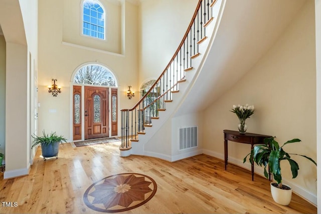 foyer entrance featuring stairs, visible vents, baseboards, and wood finished floors