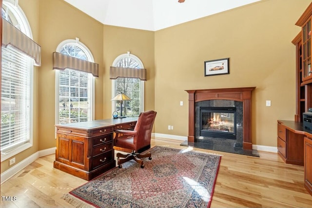 home office with plenty of natural light, baseboards, a fireplace, and light wood finished floors