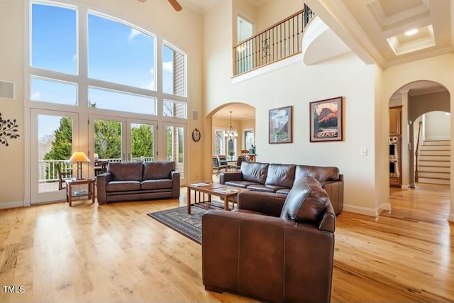 living room featuring ornamental molding, arched walkways, and light wood-style floors