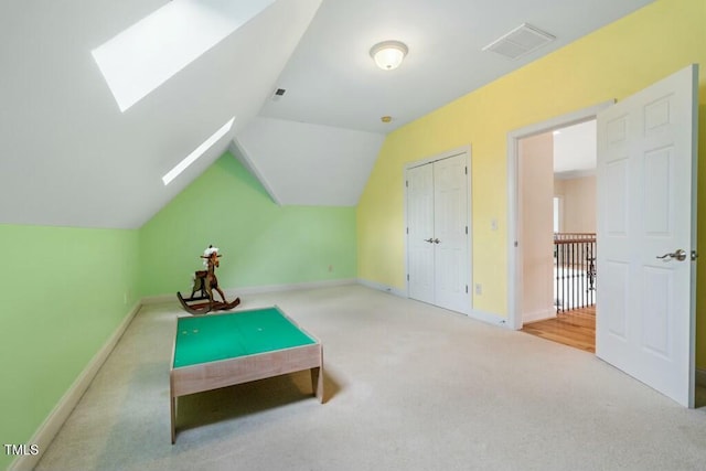 game room with vaulted ceiling with skylight, carpet, visible vents, and baseboards