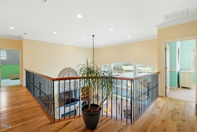 corridor with recessed lighting, wood finished floors, visible vents, baseboards, and crown molding