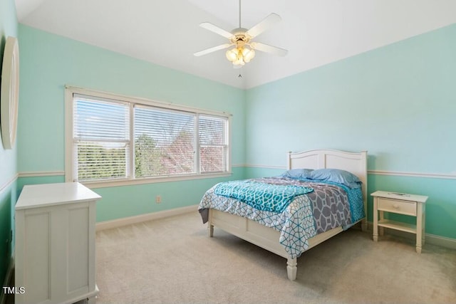 bedroom with light colored carpet, vaulted ceiling, baseboards, and ceiling fan