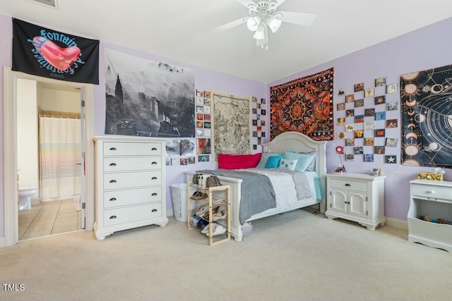 carpeted bedroom with a ceiling fan, visible vents, and ensuite bath