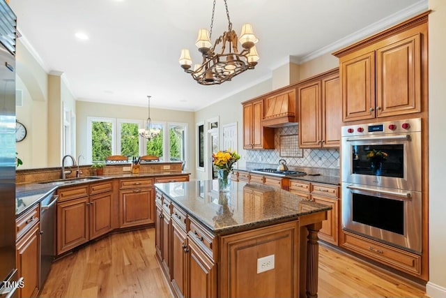 kitchen with brown cabinets, light wood finished floors, stainless steel appliances, a sink, and a chandelier