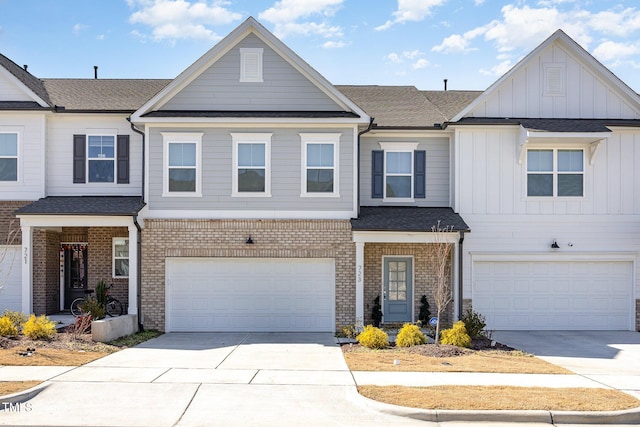 view of front of house featuring a shingled roof, concrete driveway, an attached garage, board and batten siding, and brick siding