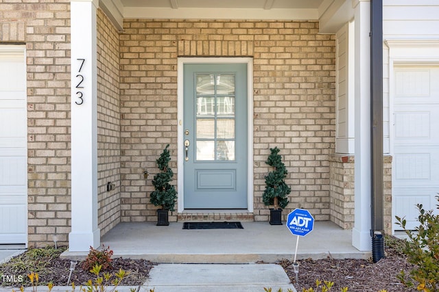 property entrance with brick siding and an attached garage