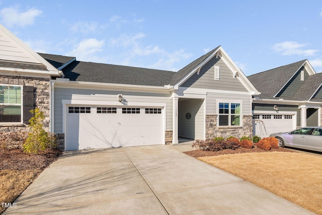 craftsman-style house featuring a garage, stone siding, roof with shingles, and driveway