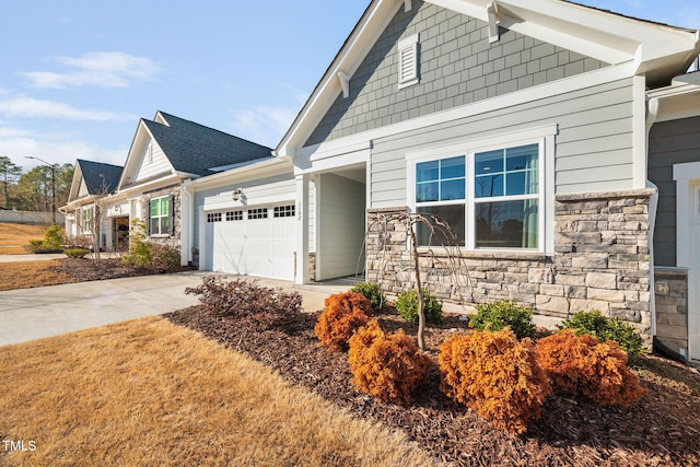 craftsman house with stone siding, roof with shingles, an attached garage, and concrete driveway