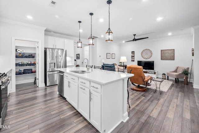 kitchen with dark wood finished floors, crown molding, a center island with sink, stainless steel appliances, and a sink