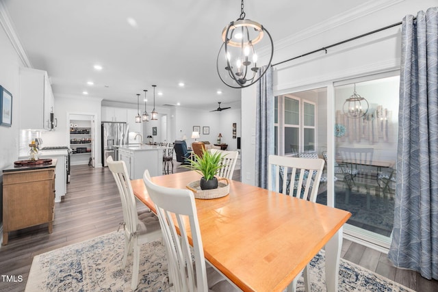 dining area featuring recessed lighting, crown molding, a notable chandelier, and wood finished floors