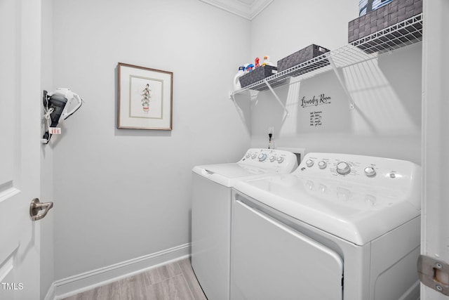 clothes washing area featuring washing machine and dryer, laundry area, baseboards, and wood finished floors