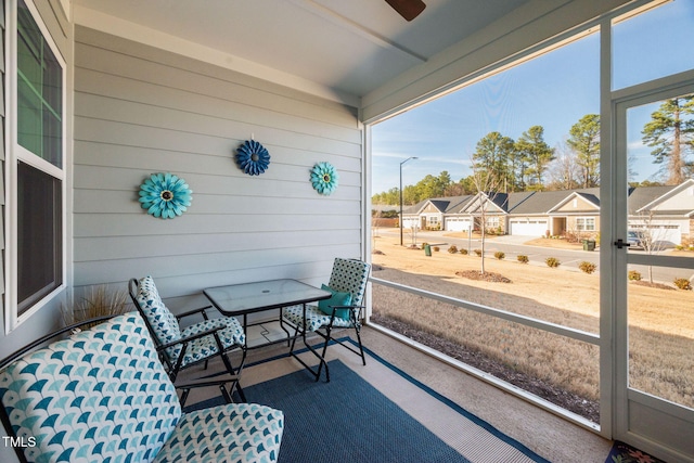 sunroom / solarium with a ceiling fan and a residential view