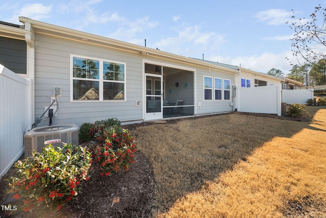 rear view of house featuring central AC, a lawn, fence, and a sunroom