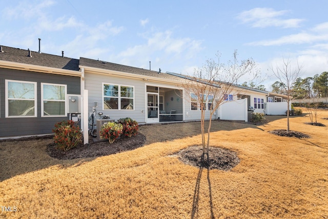 rear view of house with central AC unit and a lawn