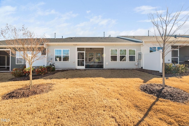 back of property with a yard, a sunroom, and fence