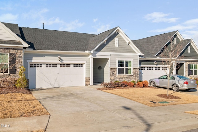 craftsman inspired home featuring a garage, stone siding, a shingled roof, and concrete driveway