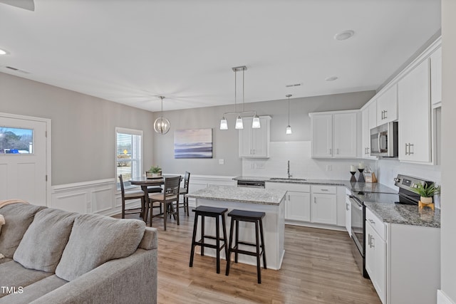 kitchen with visible vents, a breakfast bar area, open floor plan, stainless steel appliances, and a sink