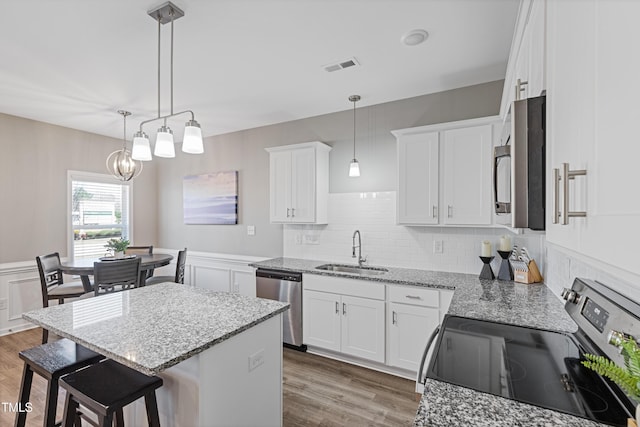 kitchen featuring wood finished floors, appliances with stainless steel finishes, a sink, and visible vents